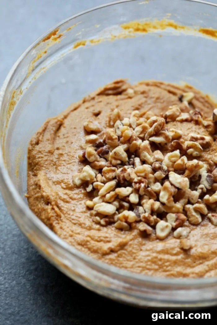 Nutritious Pumpkin Spice Muffins 5 A close-up shot of the healthy pumpkin muffin batter being gently mixed in a bowl, highlighting its smooth, consistent texture before baking.