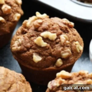 Delicious healthy pumpkin muffins, some topped with walnuts, beautifully arranged on a rustic counter.