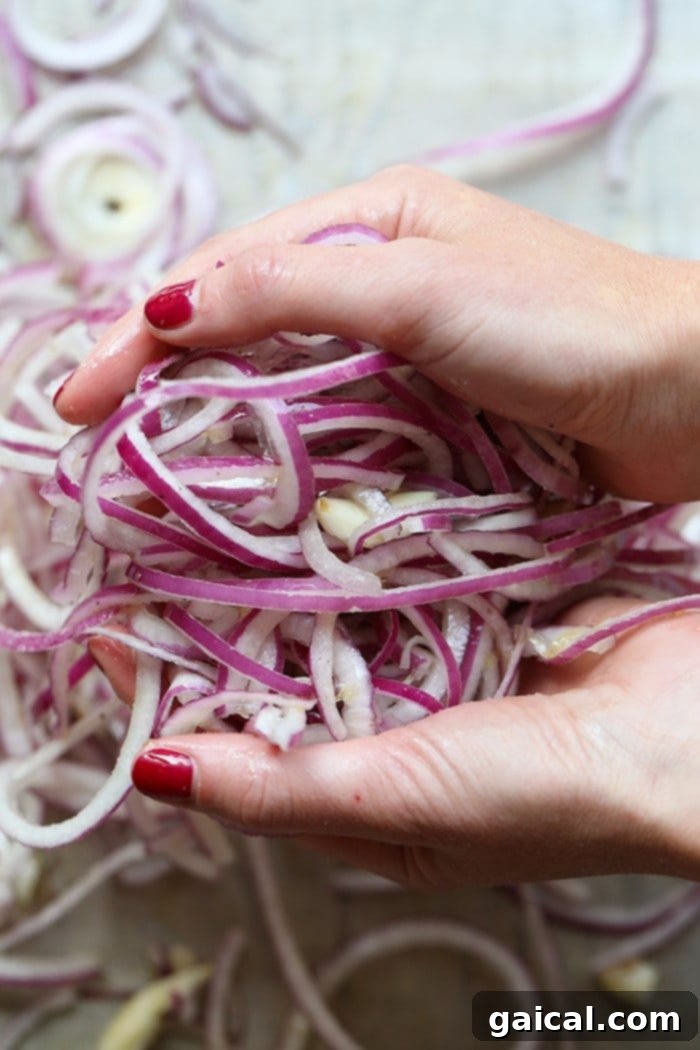 A spatula gently tossing the caramelized onions on a baking sheet, demonstrating the hands-off cooking method.
