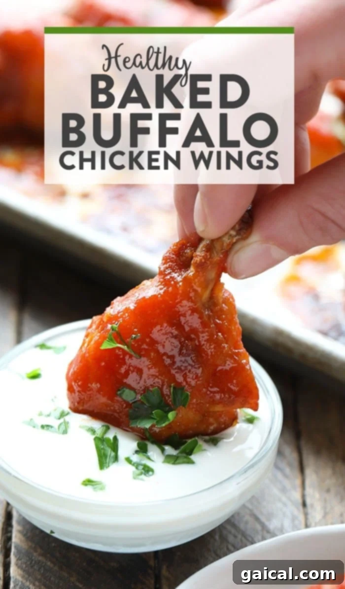 Healthy baked buffalo chicken wings, perfectly golden and coated in a vibrant red sauce, served with a side of cooling dip.