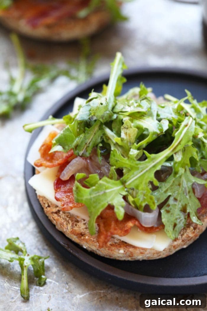 A stack of golden-brown English muffin halves, one topped with a fried egg and the other with fresh arugula, ready to be combined into a delicious breakfast sandwich.