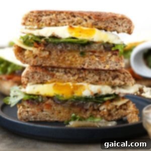 A breakfast sandwich stack with a fried egg atop toasted bread slices, ready to eat.