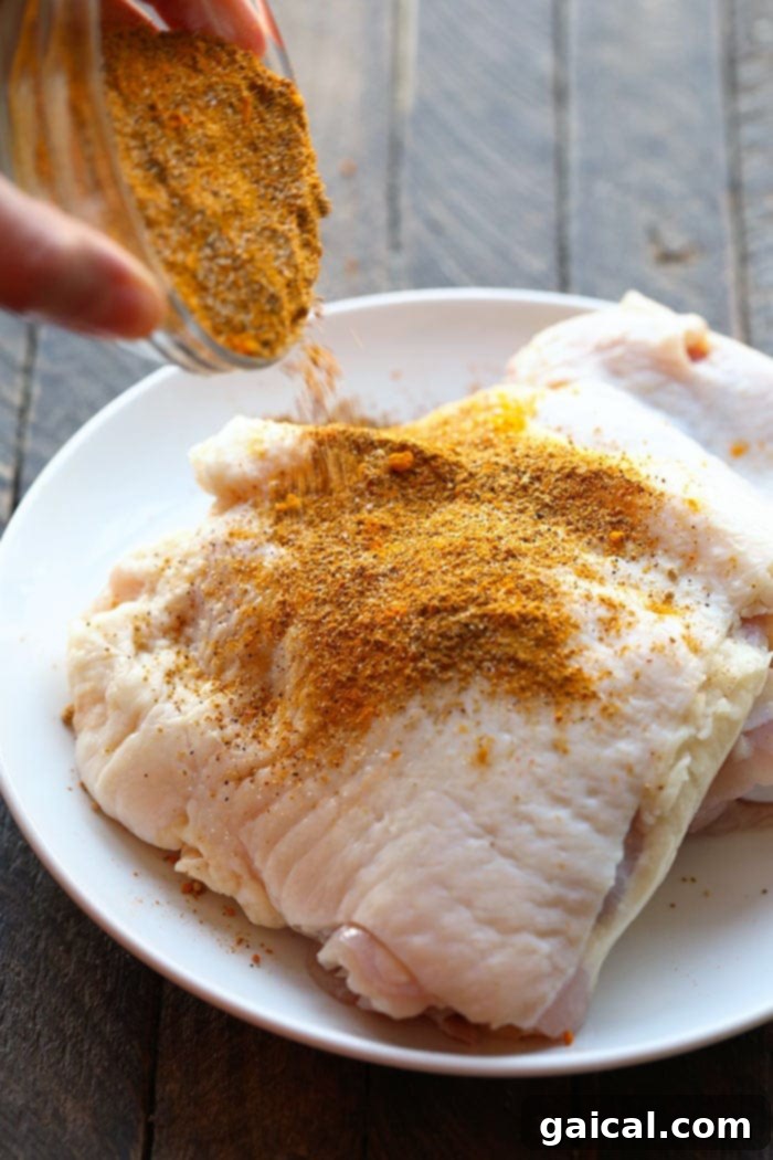Pouring dry rub onto raw chicken thighs for seasoning