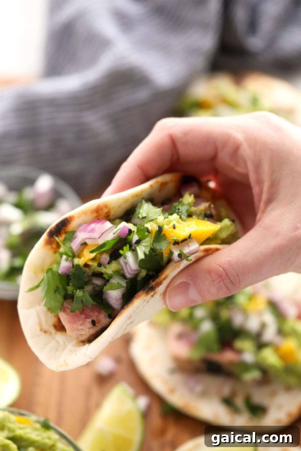 Holding an Ahi Tuna Taco A hand holding a beautifully assembled ahi tuna taco, showcasing its colorful fillings.