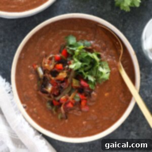 Two bowls of black bean soup on a table, garnished with fresh cilantro and a lime wedge, ready to be enjoyed.