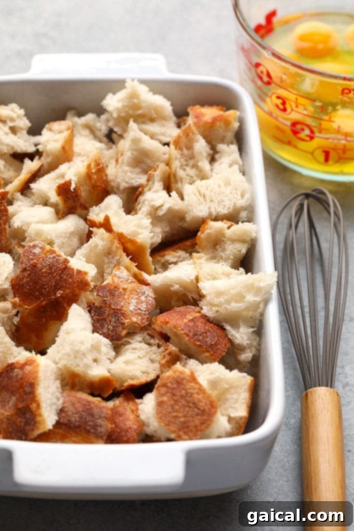 This overnight French Toast Bake is a crowd-pleasing breakfast that can be made ahead of time for easy preparation in the morning! It's served with a delicious streusel topping and maple syrup. Pieces of sourdough bread tossed in a casserole dish, ready to absorb the egg mixture for French toast bake.