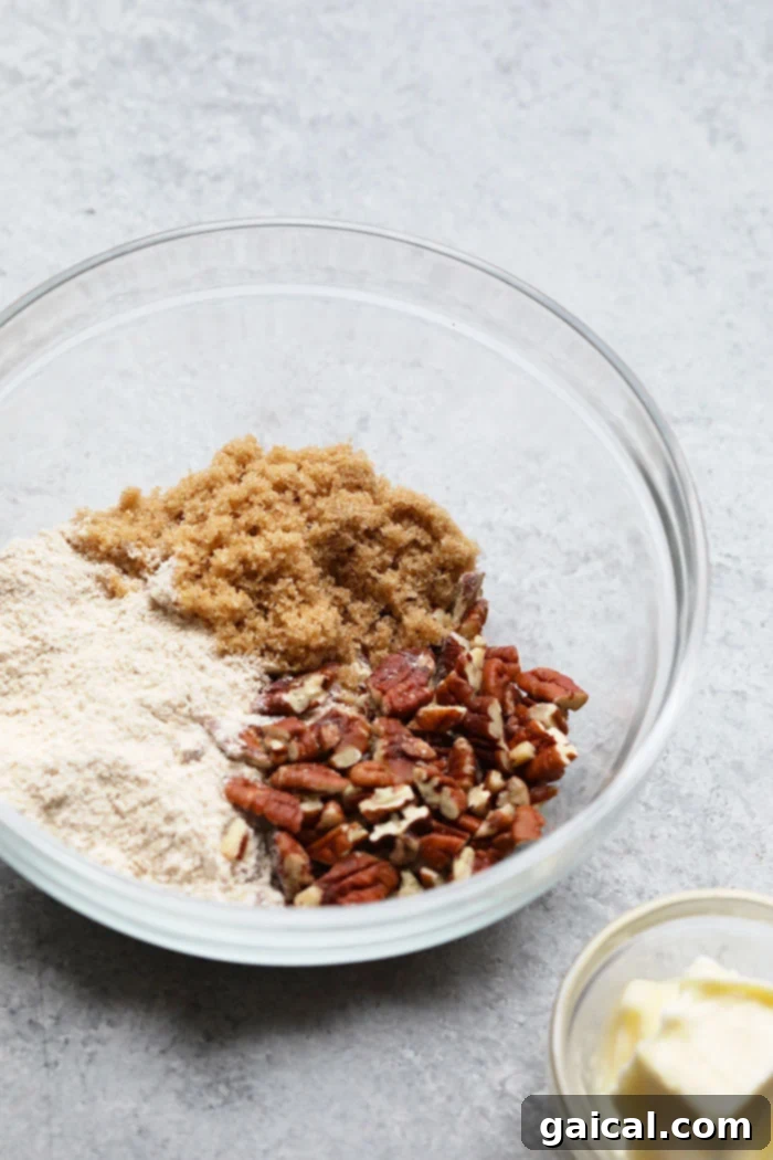 This overnight French Toast Bake is a crowd-pleasing breakfast that can be made ahead of time for easy preparation in the morning! It's served with a delicious streusel topping and maple syrup. A bowl of streusel topping, a mix of flour, sugar, butter, and pecans, ready to be sprinkled on the French toast bake.