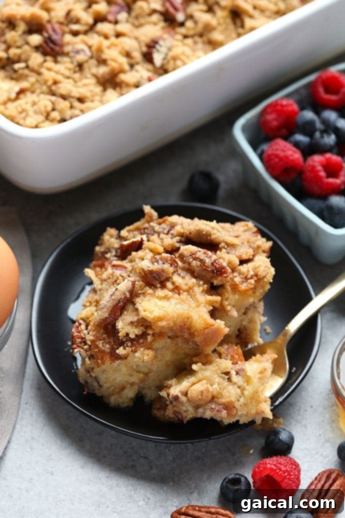 This overnight French Toast Bake is a crowd-pleasing breakfast that can be made ahead of time for easy preparation in the morning! It's served with a delicious streusel topping and maple syrup. A close-up of a single slice of overnight French toast bake, showing the streusel topping and tender bread, ready to be enjoyed.
