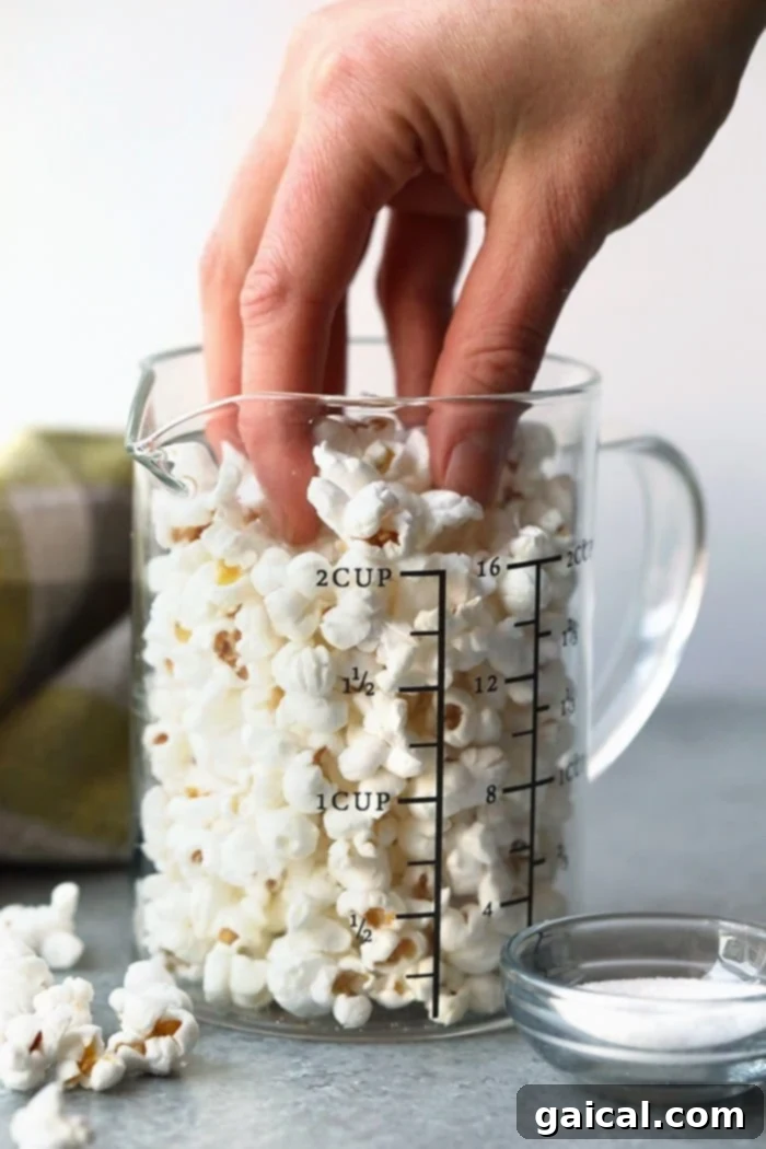 Healthy and easy homemade stovetop popcorn Hand reaching for a bowl of freshly popped stovetop popcorn