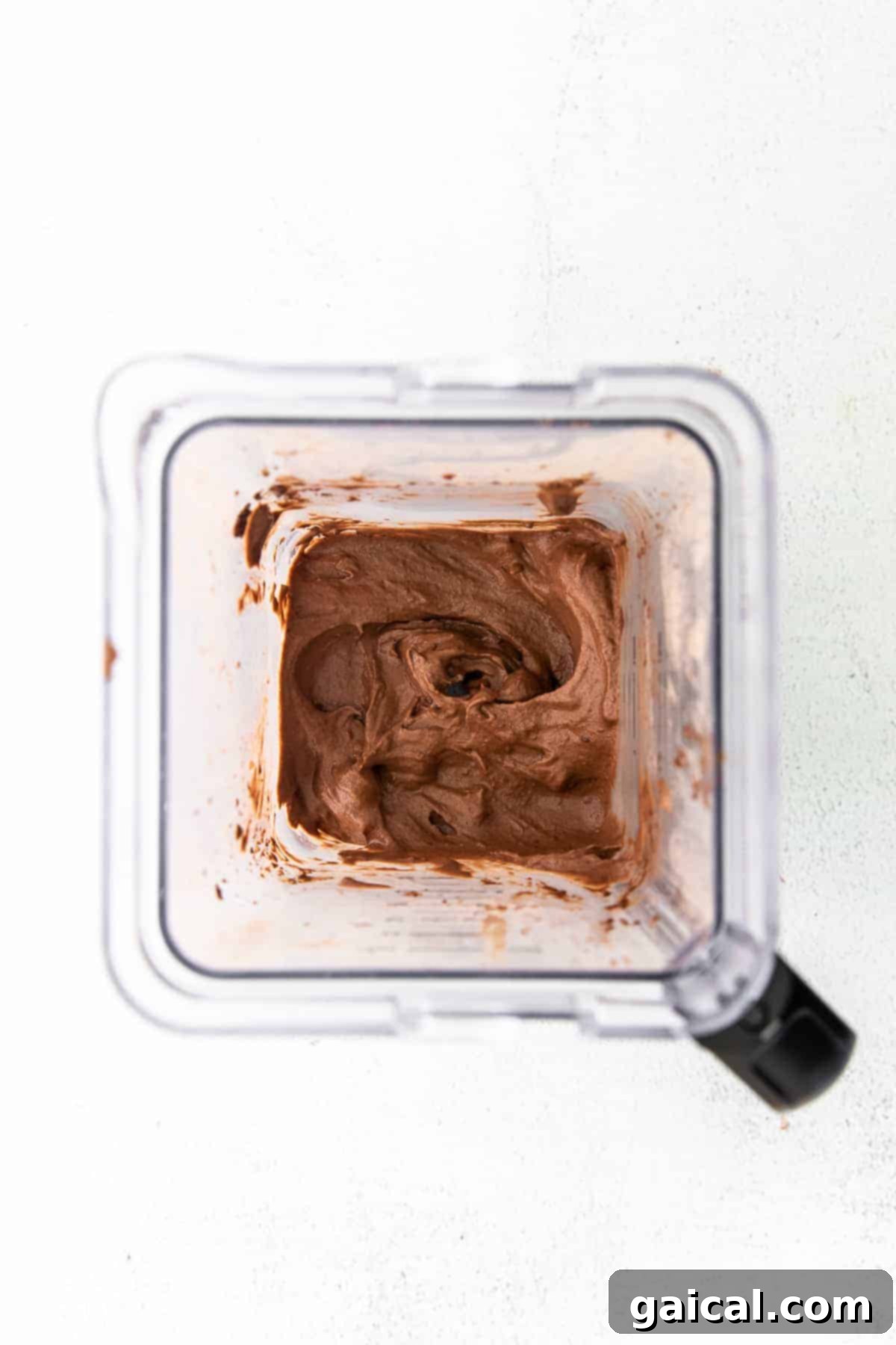 Protein-Powered Chocolate Dream 4 A high-speed blender actively mixing ingredients to create creamy chocolate protein ice cream, showcasing the smooth, swirling texture.