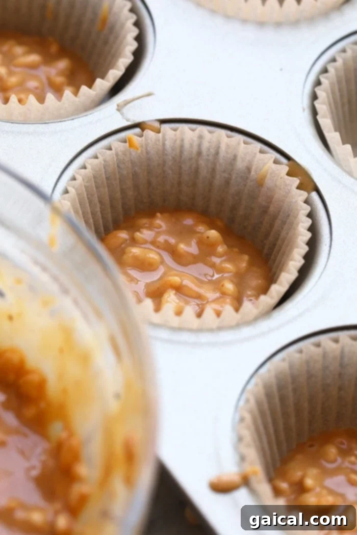 Three golden peanut butter crunch cups, two drizzled with dark chocolate and sea salt, one plain, on a textured surface.