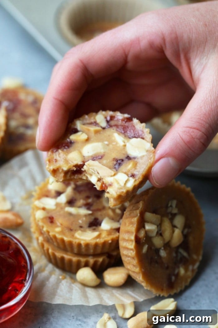 Enjoying a Freshly Made Crunchy Peanut Butter and Jelly Fat Bomb A hand holding a perfectly formed peanut butter and jelly fat bomb, showcasing its layers and crunchy topping.
