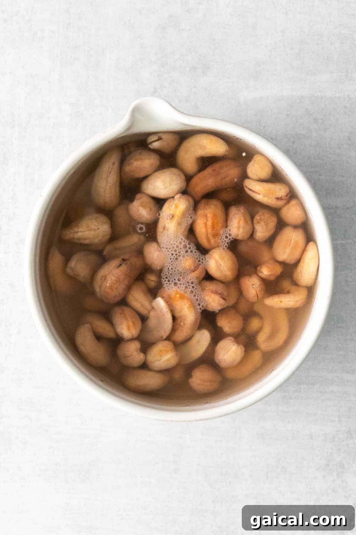 Raw cashews soaking in a bowl of water, preparing for creamy vegan pasta sauce