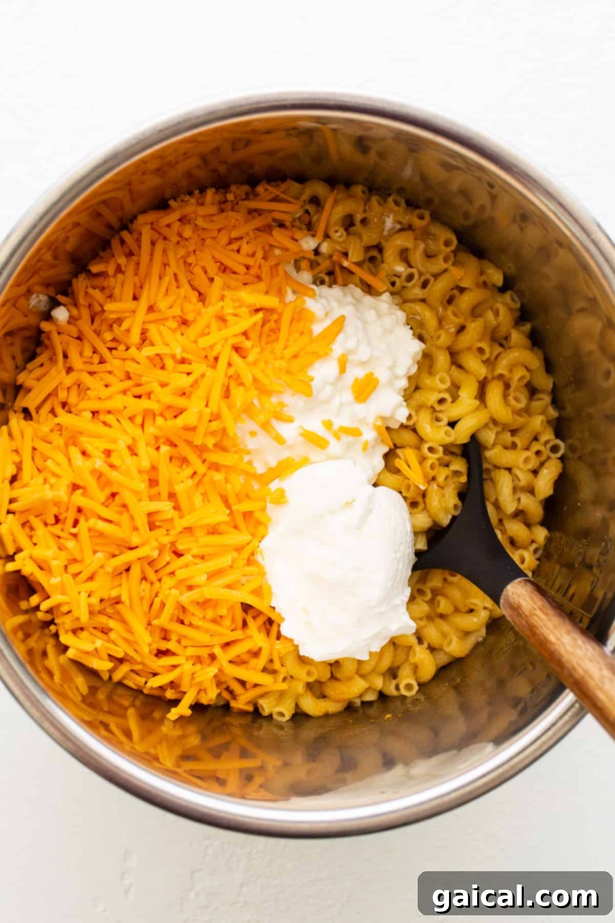 Protein-Powered Instant Pot Mac 5 Cooked macaroni noodles being stirred with melted cheese in an Instant Pot, showing the creamy texture developing.