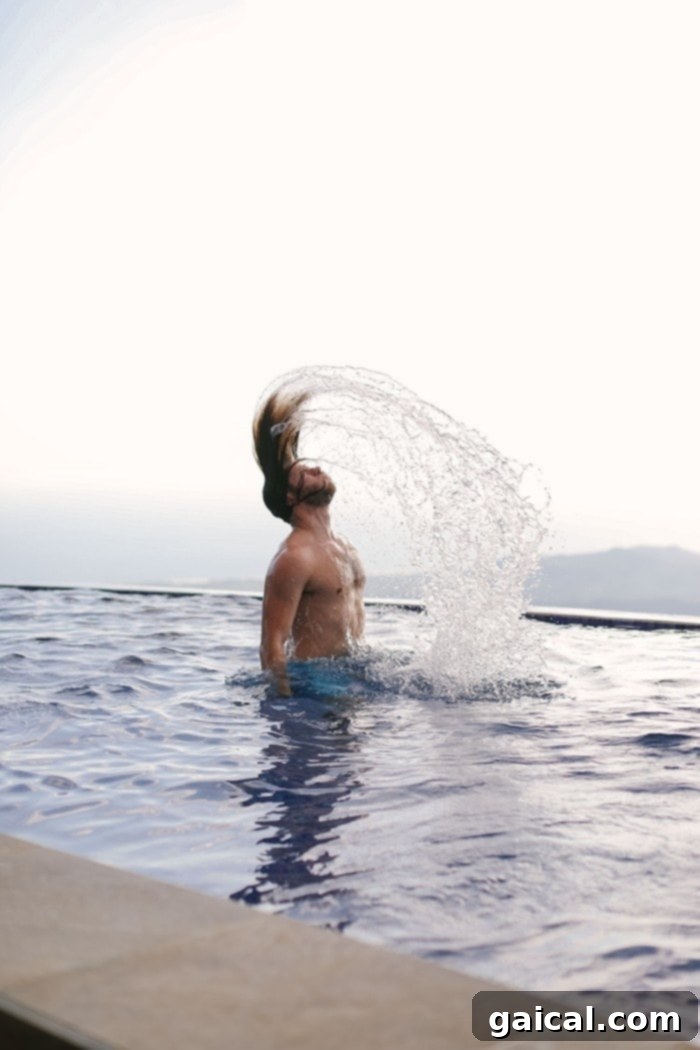 Enjoying a refreshing swim in a tropical setting Woman playfully flipping her hair while swimming in the pool