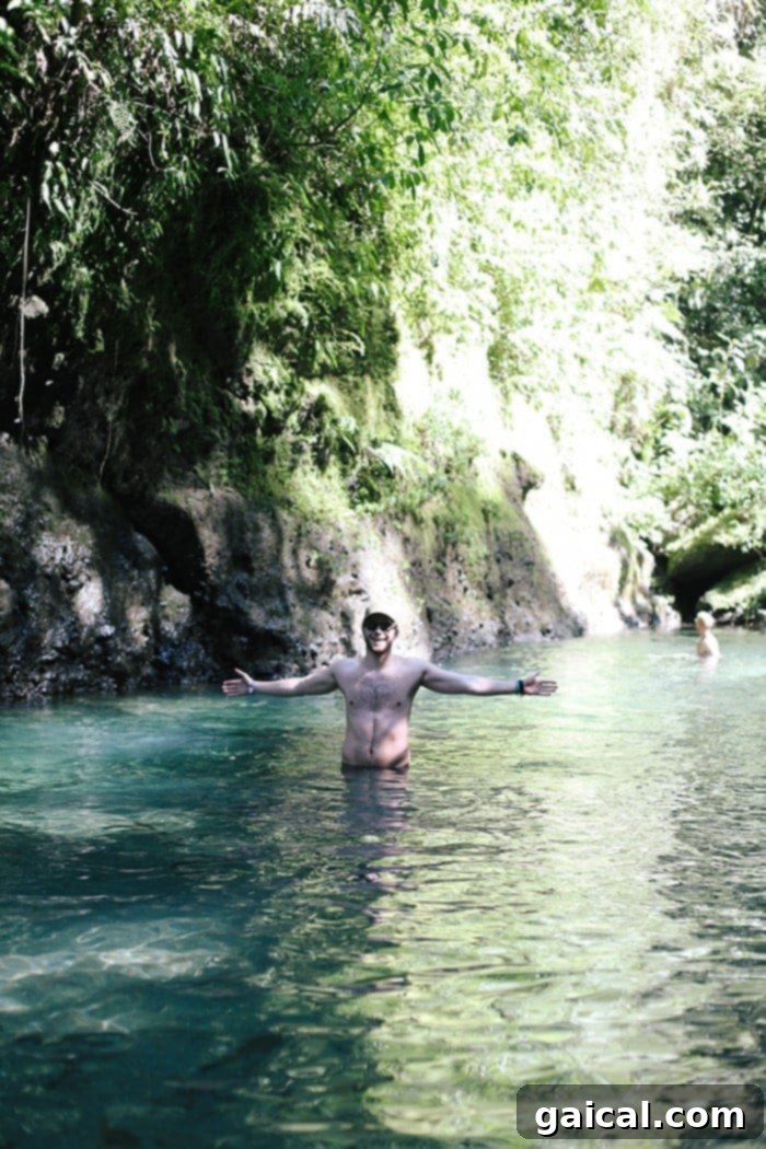 Swimming beneath the stunning La Fortuna Waterfall Man swimming in the refreshing waters below La Fortuna Waterfall