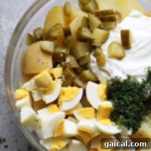 Ingredients for potato salad mixed in a bowl.