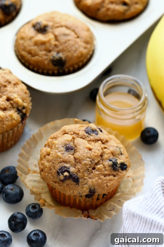 These healthy blueberry muffins are perfect for packing as a nutritious snack for work or freezing a batch to enjoy at home all week long! A batch of freshly baked, golden-brown healthy blueberry muffins cooling on a wire rack.