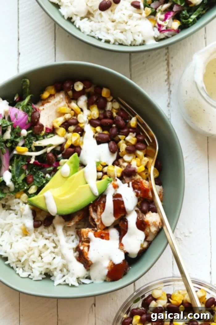 Make these bbq chicken bowls for a healthy dinner this week! You can't go wrong with grilled corn, black beans, a delicious slaw, and some bbq chicken! A beautifully prepared BBQ chicken bowl with grilled chicken, fluffy rice, vibrant slaw, grilled corn, black beans, and sliced avocado, ready for a healthy dinner.