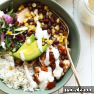 A colorful and satisfying bowl showcasing BBQ chicken, fluffy rice, seasoned black beans, grilled corn kernels, and fresh avocado slices.