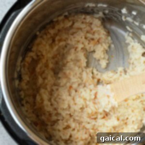 An Instant Pot filled with perfectly cooked coconut rice, being fluffed with a wooden spoon.