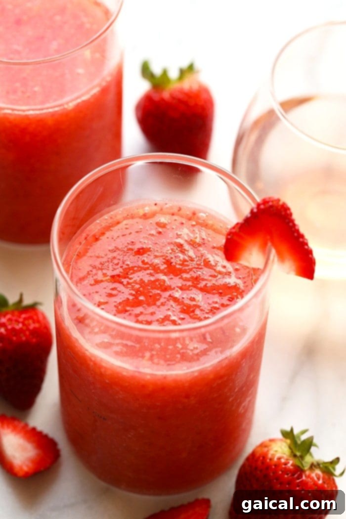 The Most Delicious Summer Drink You Ever Did See! Strawberry Peach Frosé Recipe A tall glass of vibrant strawberry peach frosé, garnished with fresh fruit, on a sunny outdoor setting, embodying the perfect summer frozen cocktail.