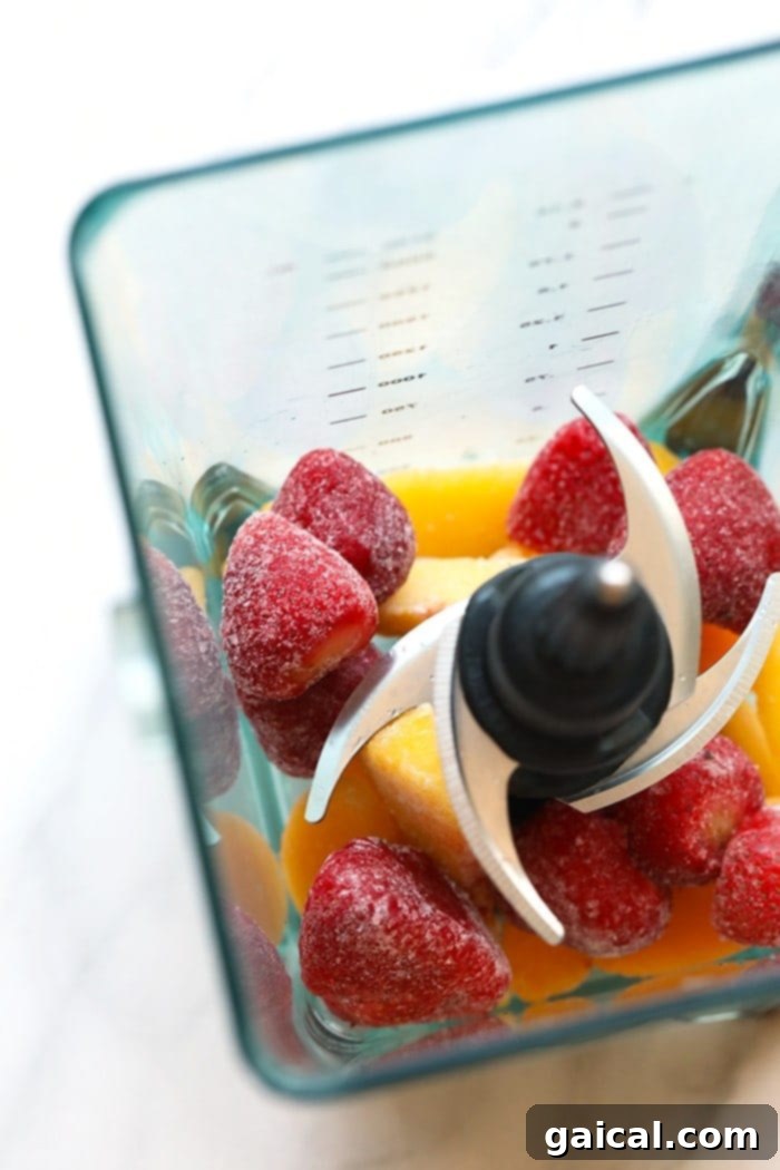 Blending the Perfect Frosé: Frozen Fruit Ready for Action A high-speed blender filled with a colorful mix of frozen peaches and strawberries, perfectly ready to be transformed into a delicious frosé.