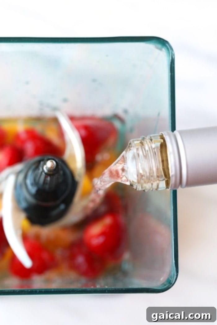 Adding Rum to Your Frosé: The Secret to Smoothness A steady stream of white rum being poured into a blender filled with frozen fruit, essential for a perfectly smooth frosé.