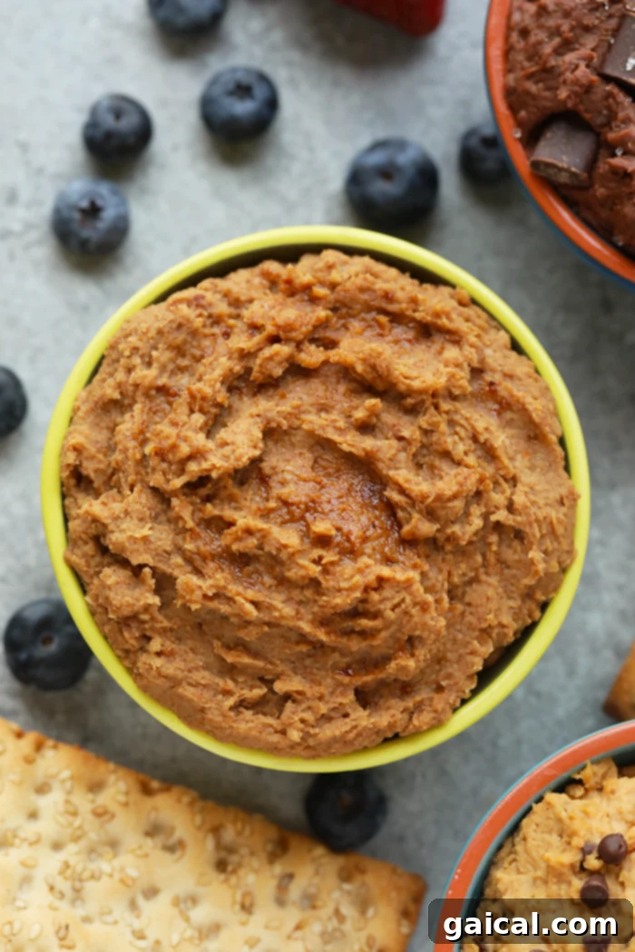 If a churro batter was edible, it would be this recipe! Made with garbanzo beans, coconut sugar, ground cinnamon, and dates, this churro edible cookie dough dip is a healthy dessert or snack option for any day of the week. A bowl of spiced Churro Cookie Dough Dip, garnished with cinnamon sugar.