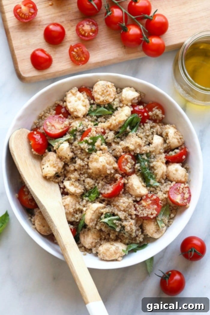 A beautifully presented Fresh Caprese Quinoa Salad in a large serving bowl, showcasing vibrant cherry tomatoes, white mozzarella pearls, green basil leaves, and fluffy quinoa.