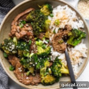 A bowl of Instant Pot Beef and Broccoli, garnished with sesame seeds and fresh green onions, ready to be served.