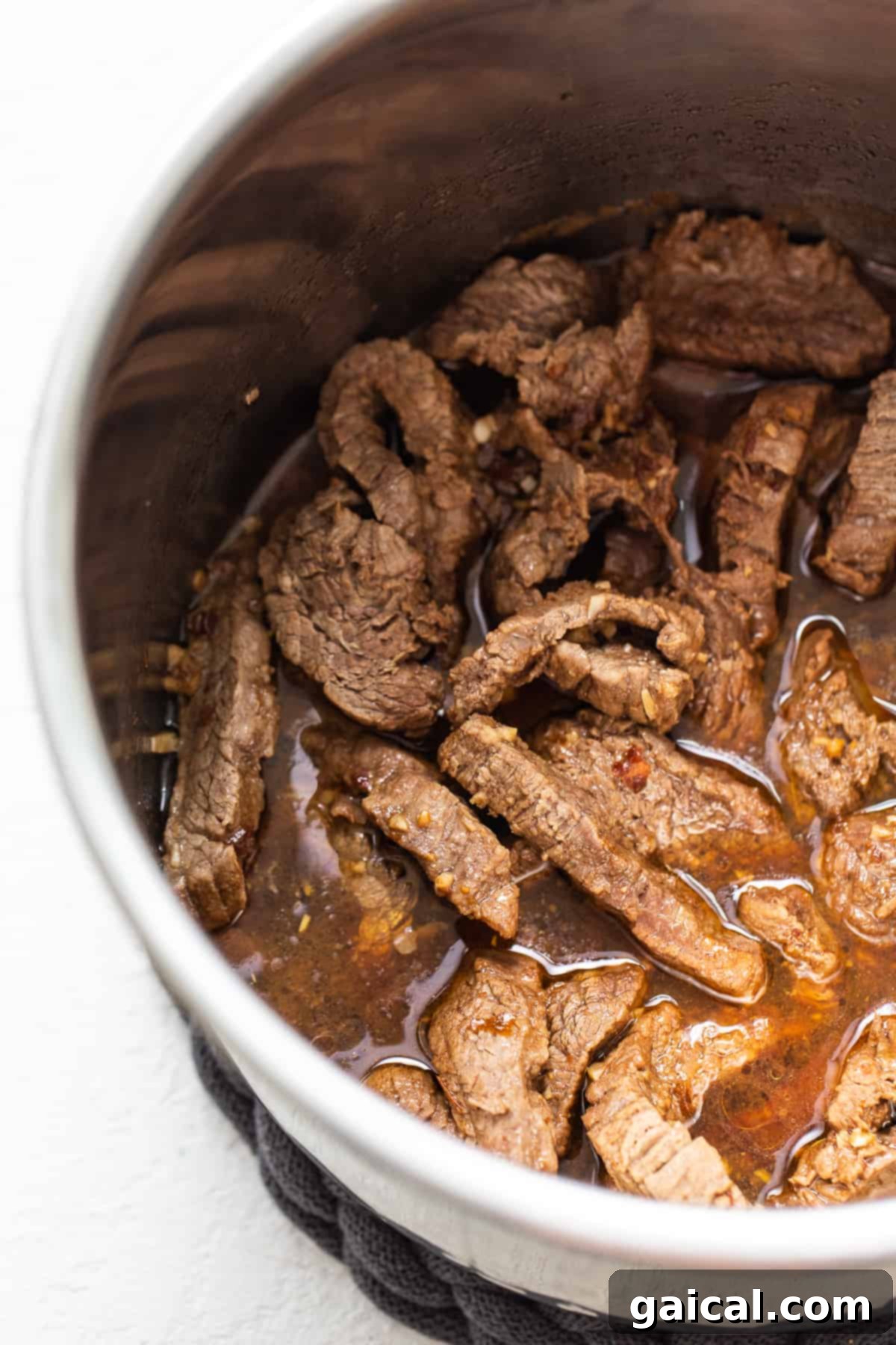 Perfectly cooked beef strips glistening in sauce inside an Instant Pot, ready for broccoli.