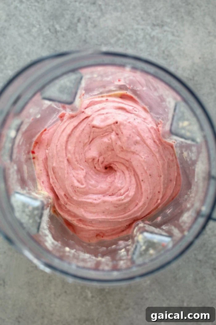 The process of blending Protein Strawberry Banana Nice Cream in a high-speed Vitamix blender, showing the creamy texture forming.