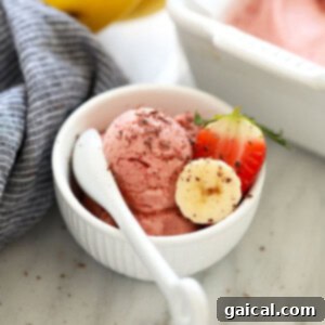A bowl of banana nice cream with fresh strawberries and a spoon, showcasing the delicious blend.