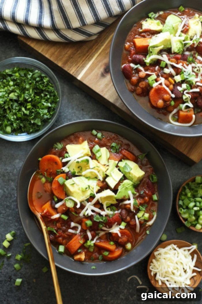 This Vegan Instant Pot Chili is an easy weeknight meal that everyone will love! It's packed with fiber from lentils and beans, as well as delicious veggies. This vegan Instant Pot Chili is the perfect meal-prep meal for the week. Make it now! Instant Pot Vegan Chili in a bowl topped with vegan cheese and avocado, ready to serve.