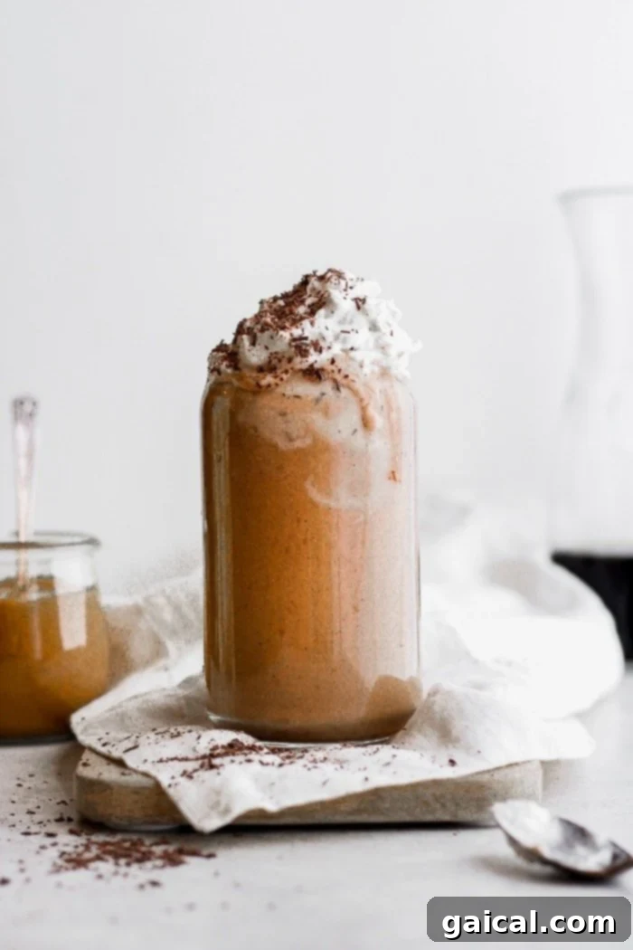 A breakfast smoothie with dairy free whip cream, topped with cocoa powder and a coffee bean