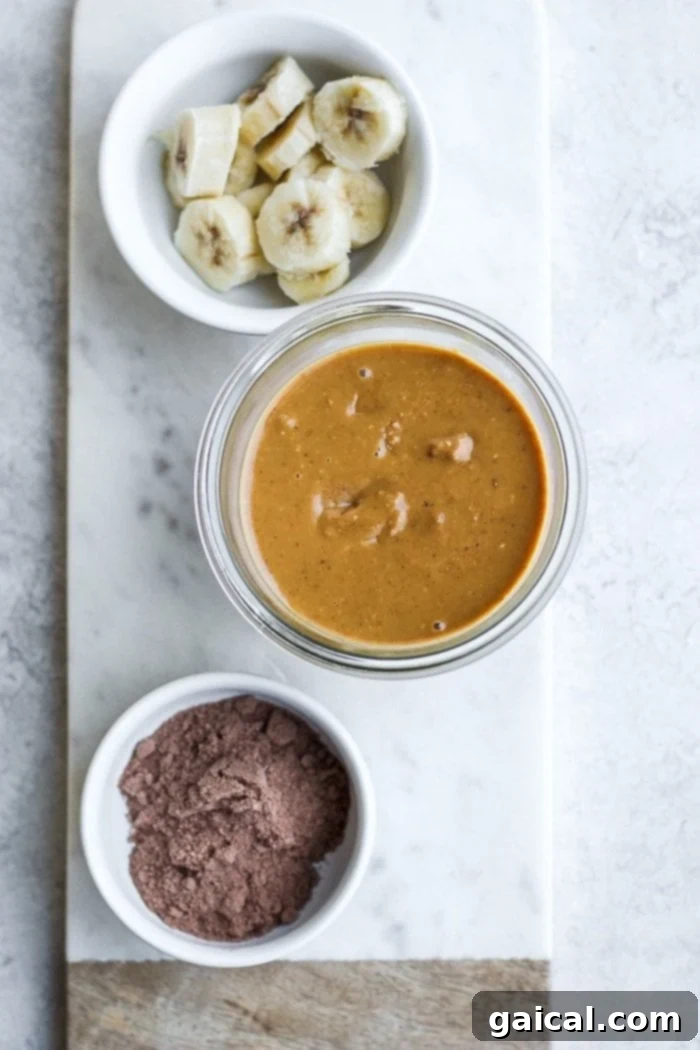 Peanut butter banana protein smoothie ingredients laid out on a kitchen counter, including frozen bananas, cold brew coffee, peanut butter, and protein powder