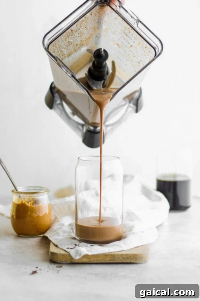 A protein smoothie being poured into a tall glass, showing its creamy texture