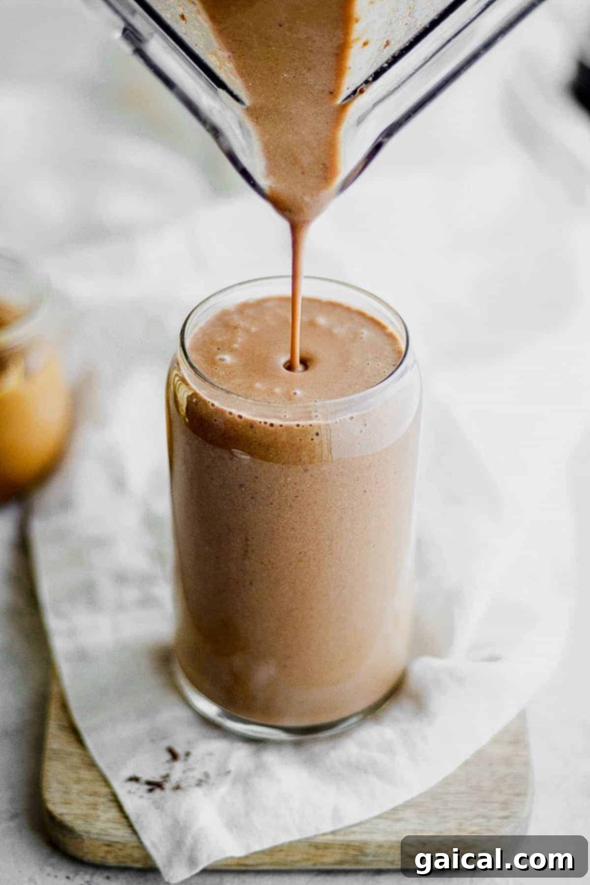 A tall glass of coffee protein shake, garnished with coffee beans
