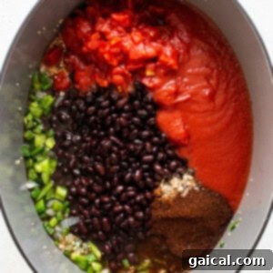 All chili ingredients, including beans, tomatoes, and spices, mixed together in a Dutch oven before simmering.