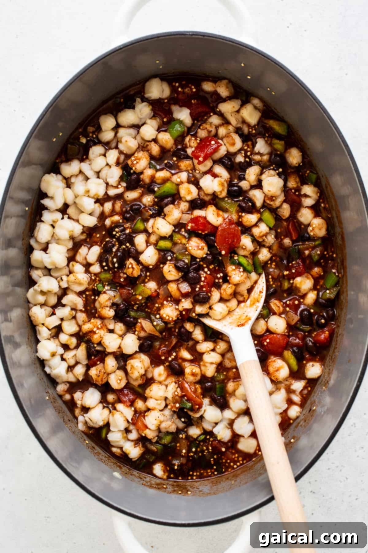 Essential black bean quinoa chili ingredients ready for the Dutch oven. A top-down view of black bean quinoa chili ingredients, including fresh vegetables, various beans, quinoa, and spices, gathered in a large Dutch oven before cooking.