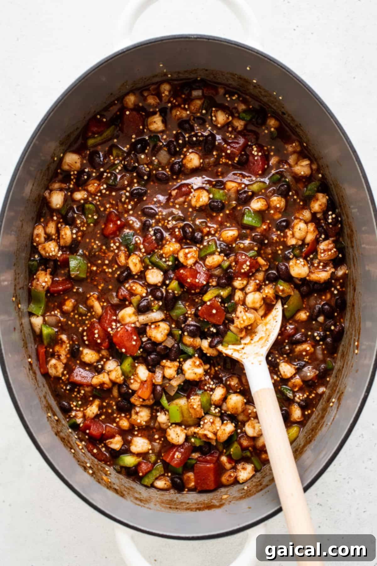 Vegetarian black bean quinoa chili simmering to perfection in a Dutch oven. A close-up shot of black bean quinoa chili simmering gently in a large, colorful Dutch oven on the stovetop, showcasing its rich, thick consistency before serving.