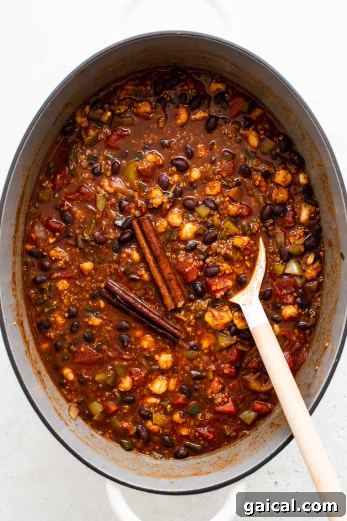 Black bean quinoa chili simmering to perfection. A close-up of hearty black bean quinoa chili simmering on the stovetop in a large Dutch oven, with steam gently rising, showing its rich, thick consistency as it cooks.