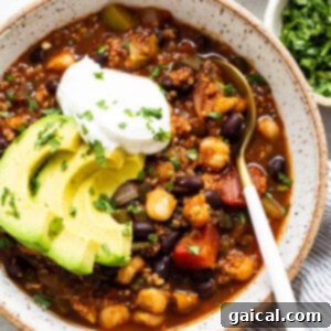 A bowl of black bean chili with avocado and sour cream, showcasing the vibrant colors and creamy toppings.