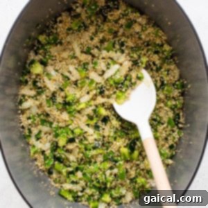 A mix of onions, garlic, and peppers sautéing with uncooked quinoa in a Dutch oven, preparing the base for the chili.