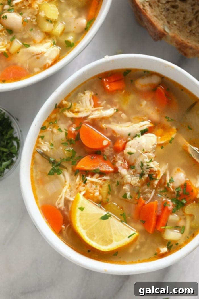 Chicken Quinoa Soup with Lemon and Parsley Two bowls of chicken quinoa soup, garnished with lemon wedges and fresh parsley, ready to be served