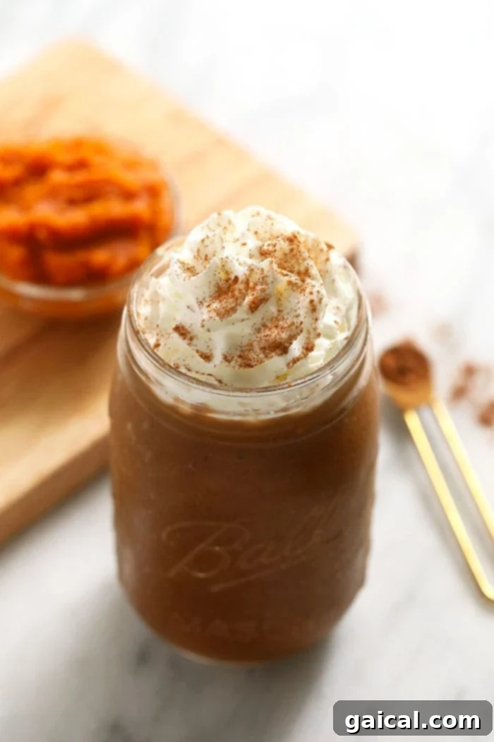 Pumpkin Spice Coffee Smoothie Delicious pumpkin spice coffee smoothie served in a clear glass jar, garnished with a light sprinkle of pumpkin pie spice on top.