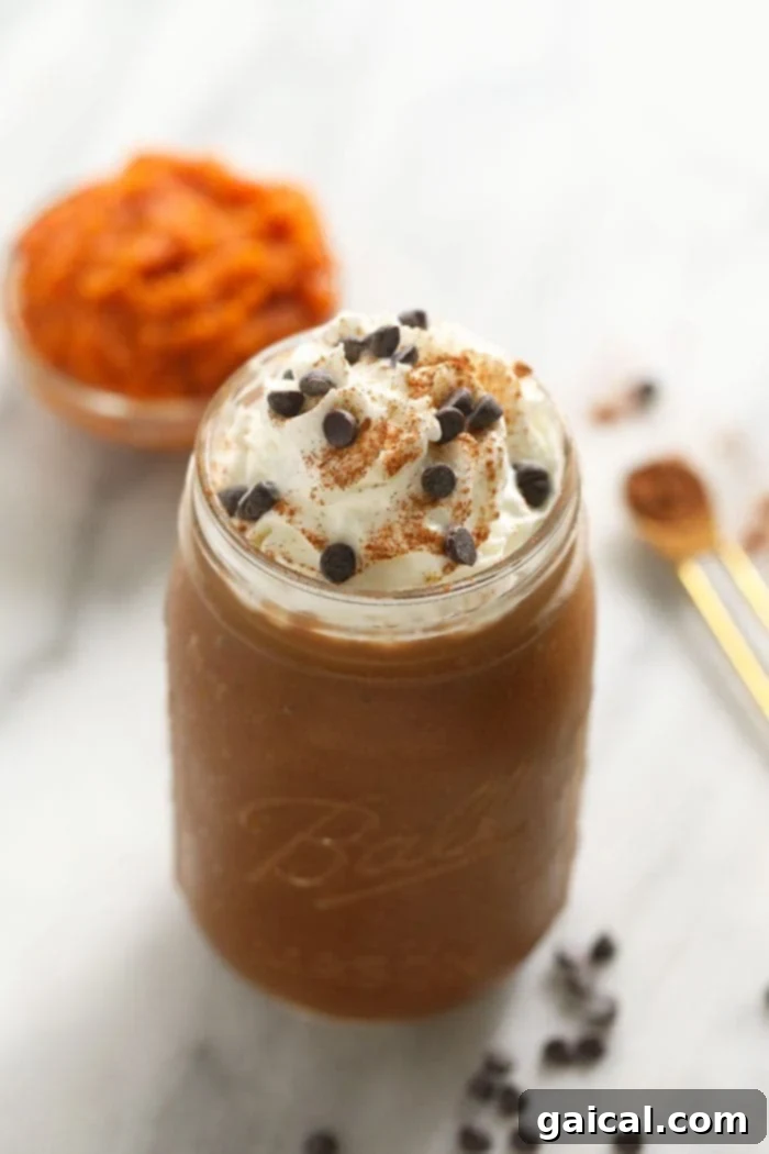 Pumpkin Pie Smoothie with Whipped Topping Close-up of a perfectly prepared pumpkin spice coffee smoothie in a clear glass jar, generously topped with a swirl of fluffy whipped cream and a dusting of vibrant pumpkin pie spice.
