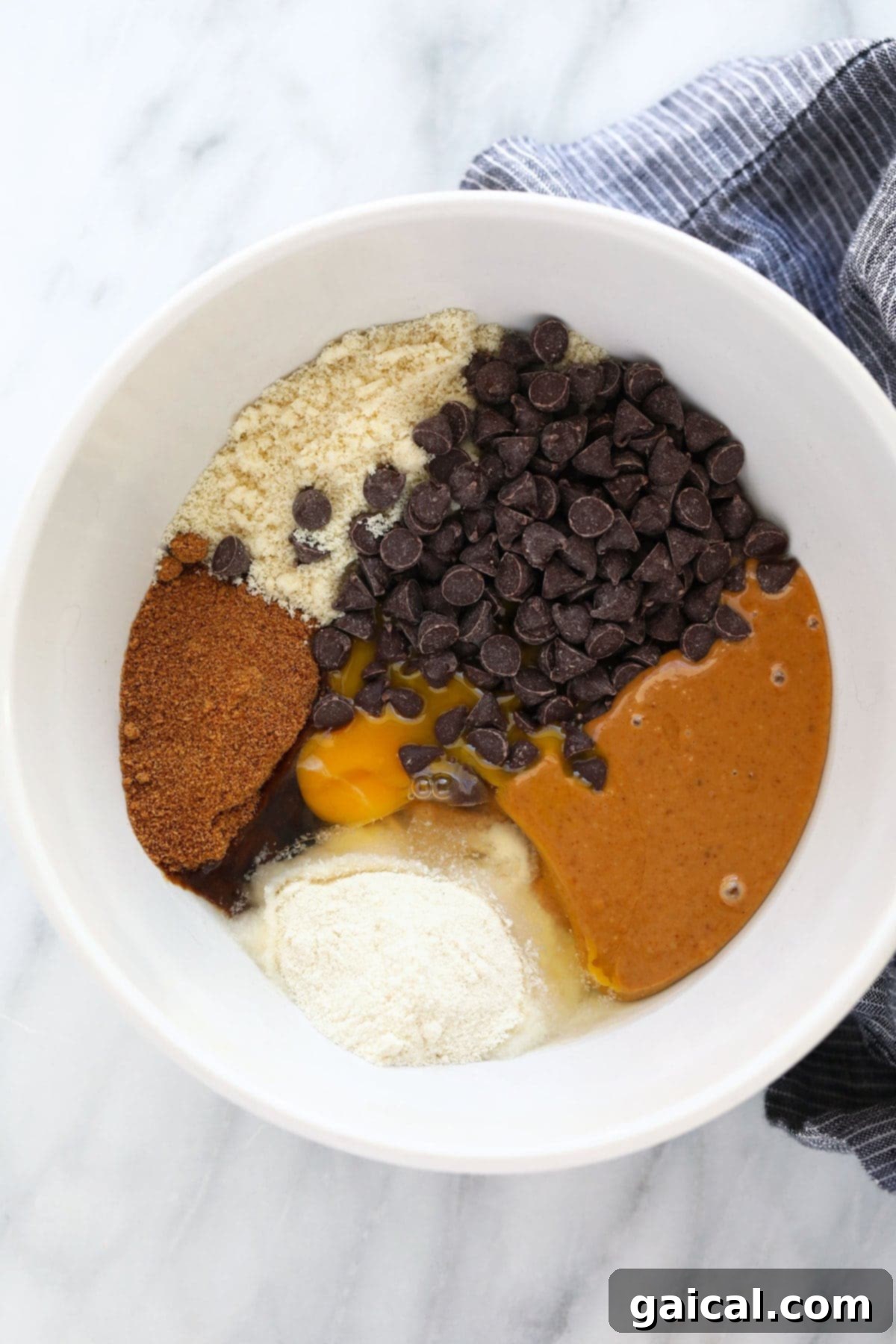 These Healthy Peanut Butter Cookies are flourless, chewy and oh so delicious with dark chocolate chips and a sprinkle of sea salt. A close-up of a mixing bowl filled with the wholesome ingredients for healthy peanut butter cookies, perfectly combined and ready to be formed.