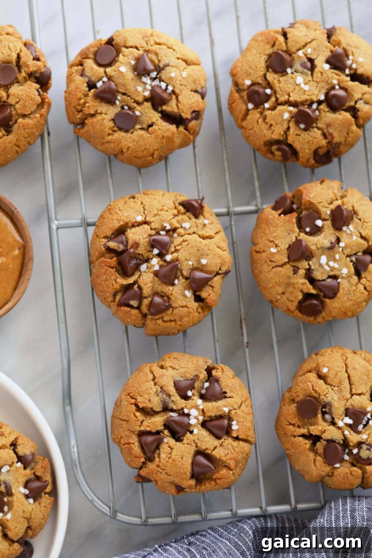 These Healthy Peanut Butter Cookies are flourless, chewy and oh so delicious with dark chocolate chips and a sprinkle of sea salt. Healthy peanut butter cookies cooling on a wire rack, showcasing their perfectly baked golden-brown exteriors and inviting texture.